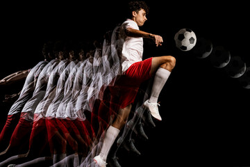 Portrait of young professional football player isolated on black background playing. Stroboscope...