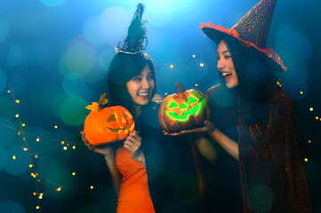 Portrait of two beautiful young woman in witch halloween costumes holding halloween pumpkin Jack O...