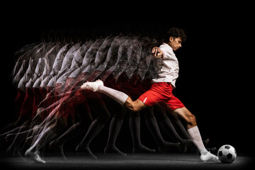 Young professional football player training isolated on black background. Stroboscope effect