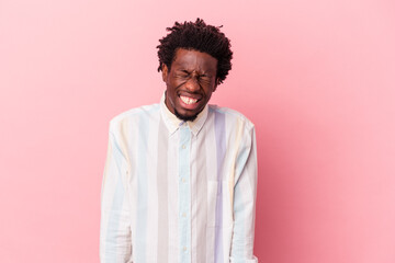 Fototapeta premium Young african american man isolated on pink background laughs and closes eyes, feels relaxed and happy.