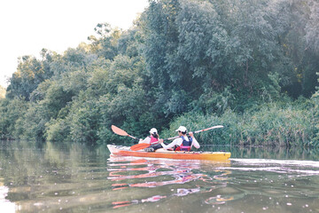 Couple kayaking on Danibe river together with green trees in the backgrounds. Having fun in leisure activity. Woman and man on the kayak. Sport, relations concept. Rear view
