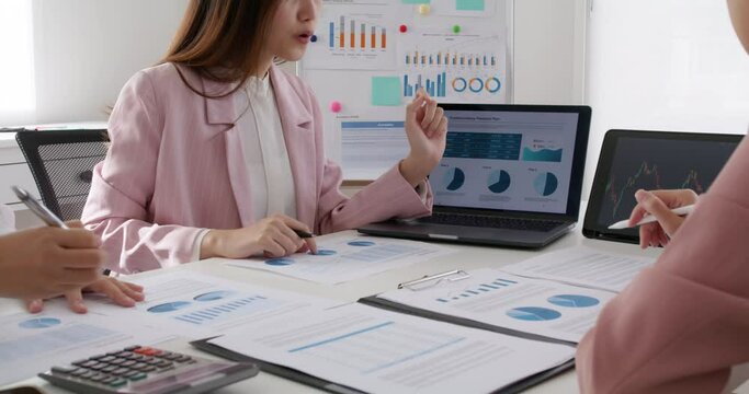 Close-up group asia woman people talk in budget plan report brief idea on chart graph data in paper work on laptop tablet at desk table office in tax loan consult career, stock broker or trader job.