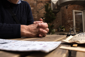 Man with hands clasped together and resting on a table outside