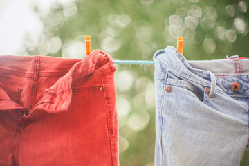 red and blue jeans hanging on a rope with clothespins in the garden