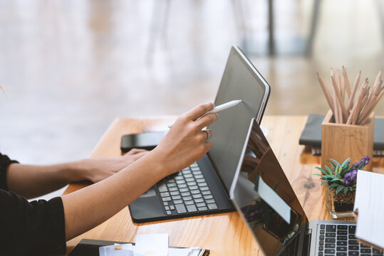 Image of a business woman holding a stylus working using a tablet at the office.