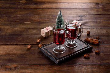 Christmas mulled red wine with spices and fruits on a dark table.