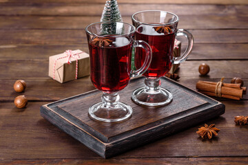 Christmas mulled red wine with spices and fruits on a dark table.