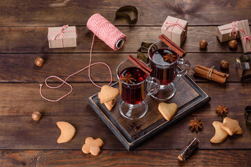 Christmas mulled red wine with spices and fruits on a dark table.