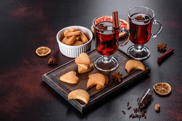 Christmas mulled red wine with spices and fruits on a dark table.