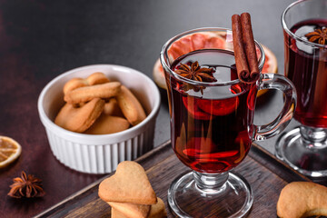 Christmas mulled red wine with spices and fruits on a dark table.