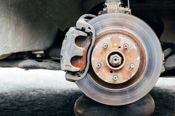 Rusty back car wheel hub with brake disc at tire shop. Car without wheel while replacing on the...
