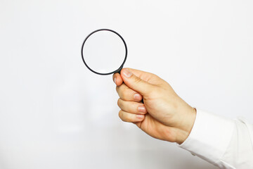 A businessman in a white shirt is holding a magnifying glass. white background. business and finance