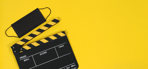 Clapper board or movie slate and black face mask on yellow background. Yellow and black color.