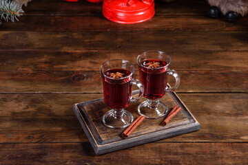 Christmas mulled red wine with spices and fruits on a dark table.