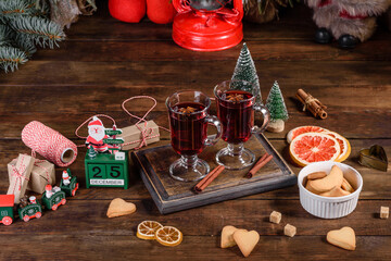 Christmas mulled red wine with spices and fruits on a dark table.