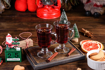 Christmas mulled red wine with spices and fruits on a dark table.
