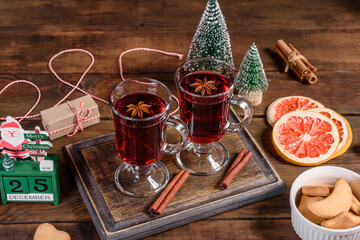 Christmas mulled red wine with spices and fruits on a dark table.