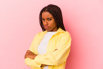 Young african american woman isolated on pink background  frowning face in displeasure, keeps arms folded.