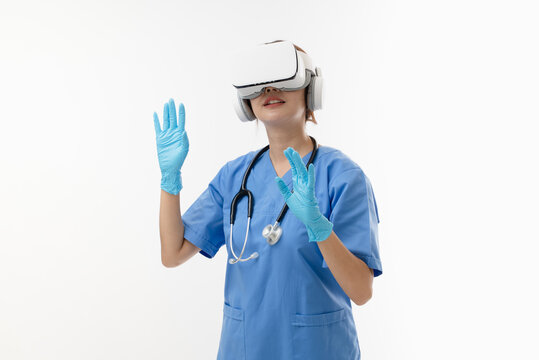 Young Female Asian Doctor Wearing Blue Scrubs With Stethoscope Using VR Virtual Reality Glasses Simulator Isolated In White Background