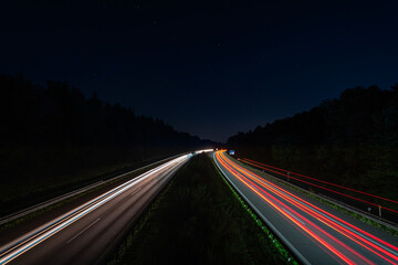 Lighttrails of a traffic motorway from the cars front and headlights, passing fast the point ov...