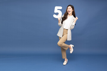 Young Asian business woman showing number 5 or five isolated on deep blue background, Full body...