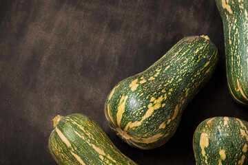 Fresh and green elongated pumpkin on a black wooden table 
