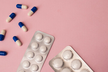 Some different pills and envelope of pills on a pink background with copy space 