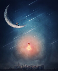 Surreal scene over the night city with a creative boy seated on the crescent moon using a fishing...