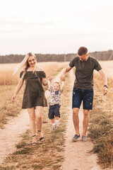 Young parents mom and dad walk in the summer in nature with their young son