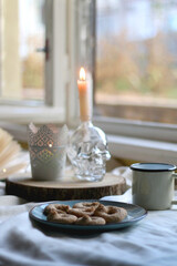 Plate with cookies, open book, lit candles and fairy lights. Hygge at home. Selective focus.