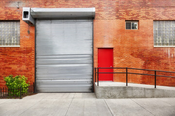Empty street with brick wall building with automatic rolling shutter, New York, USA.
