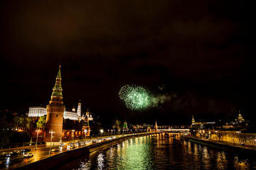 fireworks over the night river with floating motor ships of the embankment and the old Kremlin 