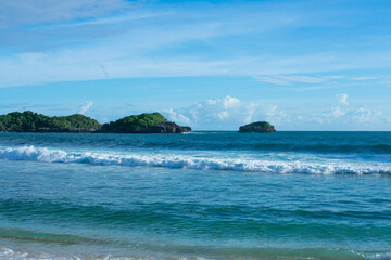 A beach with a small island with sunny weather.