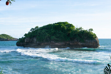 A beach with a small island with sunny weather.