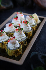 Rolls in tempura with mussels. Traditional Japanese cuisine. Raspberry tobik caviar. Ebi tempura. White ginger. Cocktail shrimp. Vertical photo on a black background. Close-up. Out of focus.