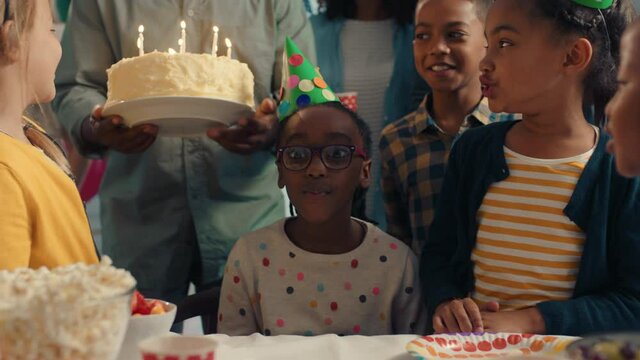 adorable birthday girl blowing candles on cake making wish celebrating party with friends and family children having fun celebration at home 4k footage