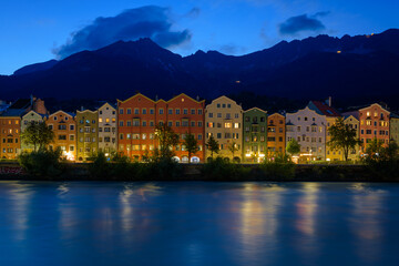 Fototapeta na wymiar Colored houses on the Inn river with the mountains in the background at night, Tyrol, Innsbruck, Austria