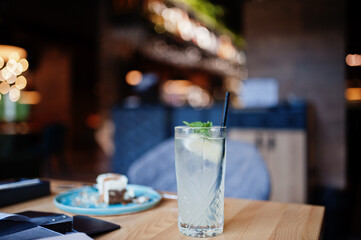 Cool freshly made lemonade in glass on wooden table at restaurant.