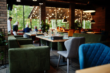 Set table in a restaurant with cozy interior, glasses, fork, knife served for dinner.