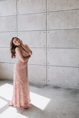 a beautiful girl with long hair in a pink dress advertises clothes and smiles