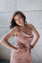 Fototapeta premium a beautiful girl with long hair in a pink dress advertises clothes and smiles
