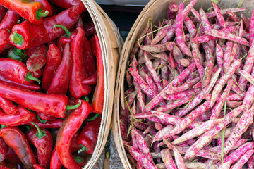 Pink and white Borlotti or cranberry beans are seen with red peppers at the market.