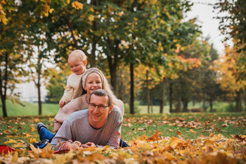 family pretend pyramid autumn park sitting between trees, smiling together.leaf fall, lifestyle.