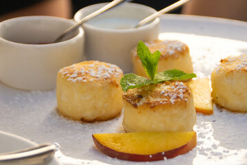 A plate of traditional slavic little cheesecakes with peach slices