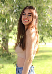 Fototapeta premium Beautiful toothy smiling teen woman looking happy outdoors summer green trees background. Closeup portrait