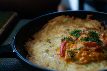 A pan with a huge potato pancake and stewed vegetables