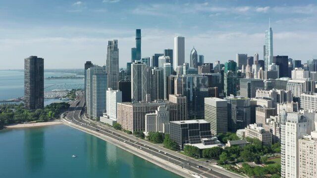 Flying above Chicago Downtown skyline at sunrise. Busy city road by the shore with cars. Prestige luxury real estate property apartment buildings with lake Michigan view. Early morning urban view 4K