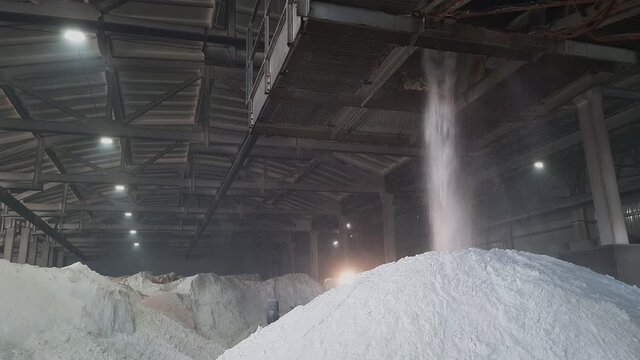 Ammonium sulfate powder pour in a pile inside a warehouse of chemical plant. Mineral organic fertilizers for agriculture industry.