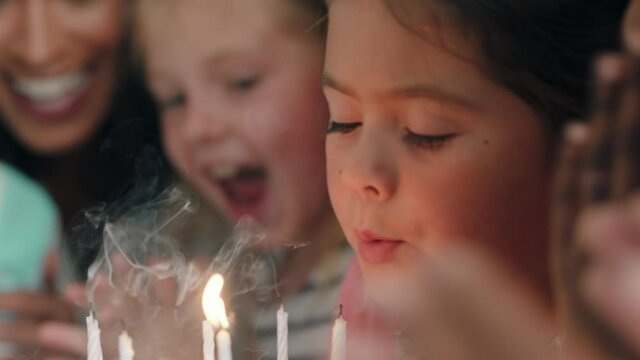 happy little girl birthday party blowing candles on cake making wish celebrating with friends children having fun celebration at home 4k footage