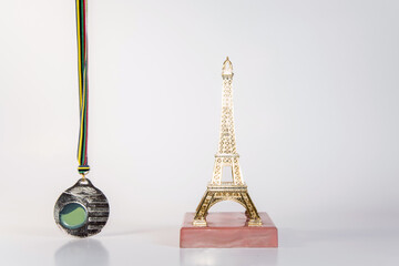 Estatuilla dorada de la Torre Eiffel junto a una medalla sobre fondo blanco. Recuerdo souvenir de...